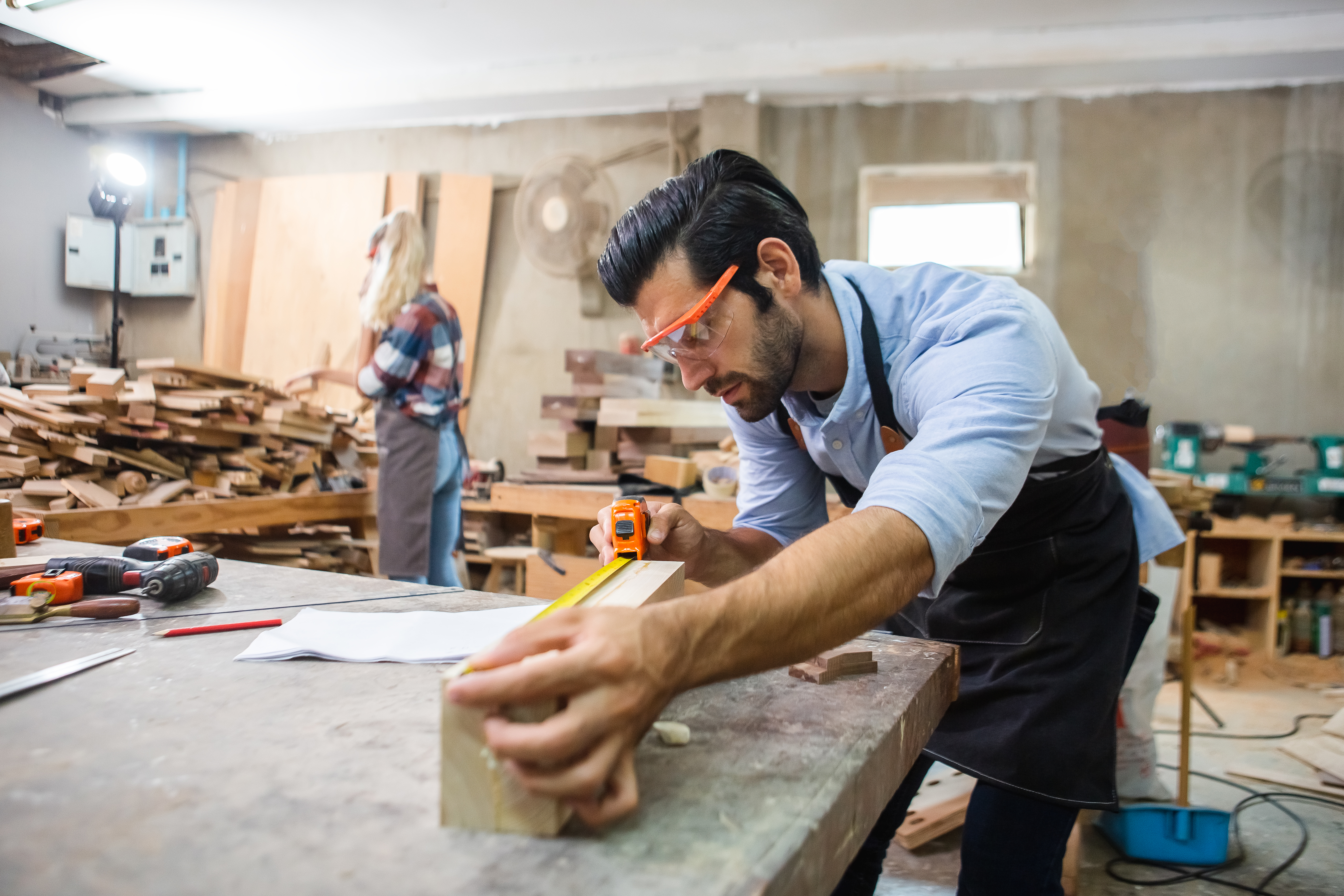 Young carpenter using measuring tape